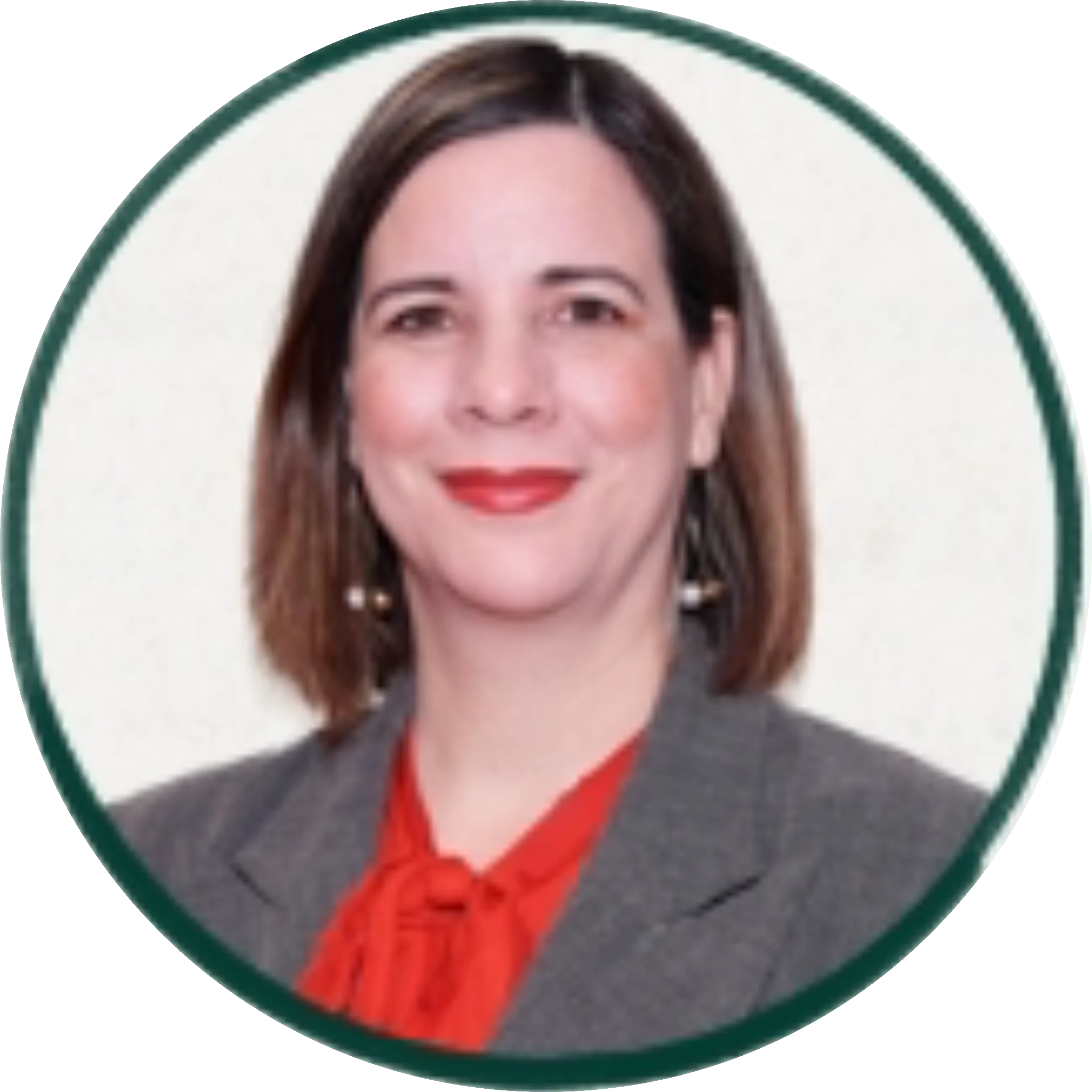 Professional headshot of a woman with shoulder-length brown hair, red lips, wearing a gray blazer over a red blouse with pearl earrings